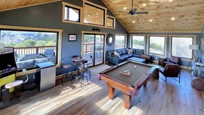Un grand espace intérieur comprenant une table de billard, des sièges et une autre table de billard offrant une vue sur l’extérieur.