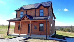 Une maison en bois à deux étages, dotée d’un toit à pignon et d’un porche à l’avant.