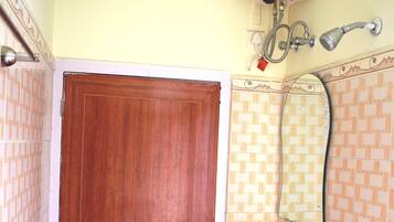 A bathroom with a wooden door, a white sink, a mirror, and a wall-mounted heater.