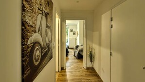 Een hal met een houten vloer, een deur aan de rechterkant en een schilderij aan de linkerkant.