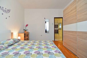 A bedroom with a bed, a bedside table with a lamp, a mirror, and a wooden wardrobe.