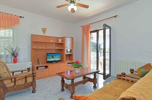 A living room with a sofa, a coffee table, a TV, and a wooden cabinet.