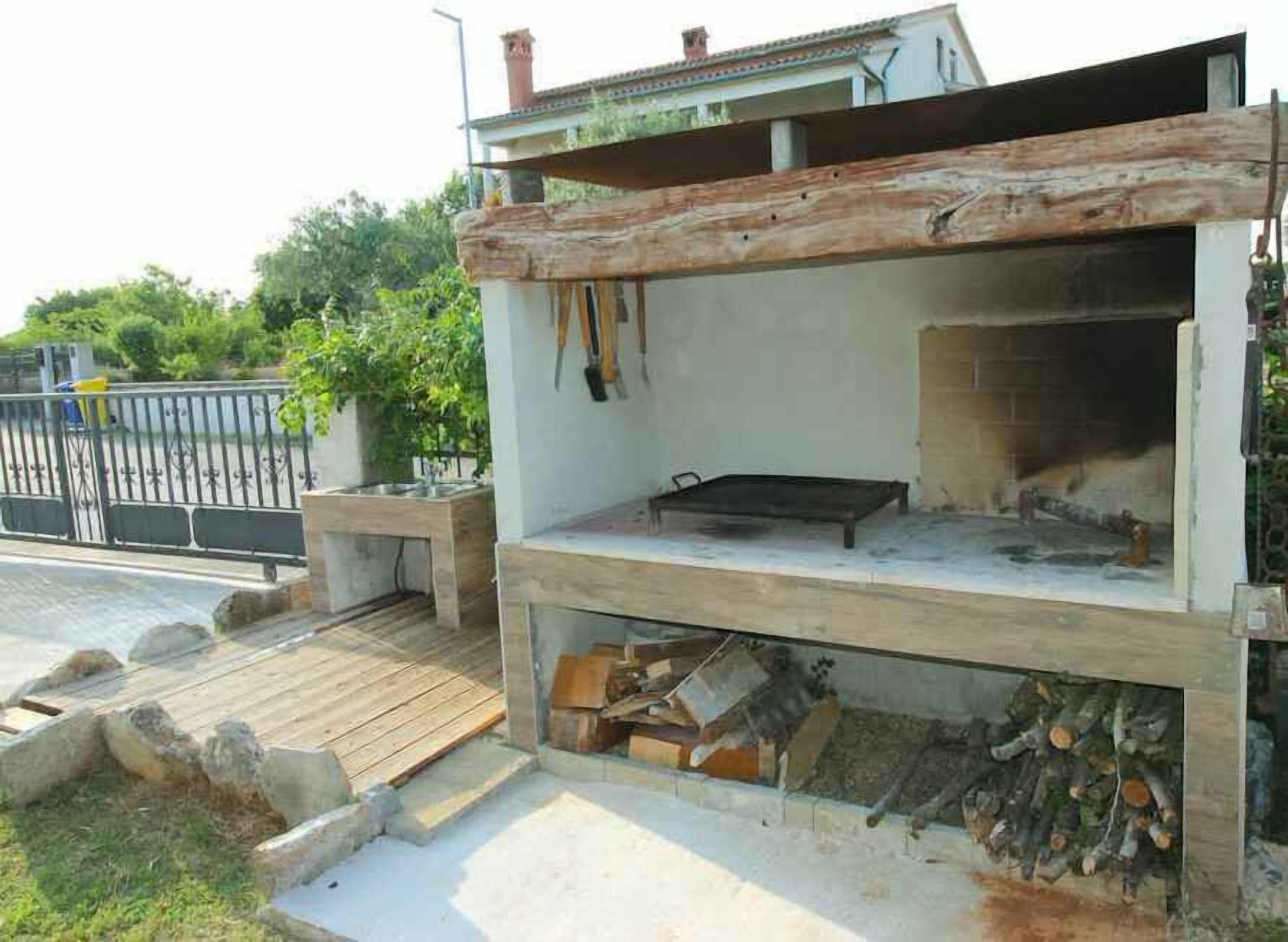 An outdoor kitchen with a built-in grill, a wooden deck, and a stone bench.