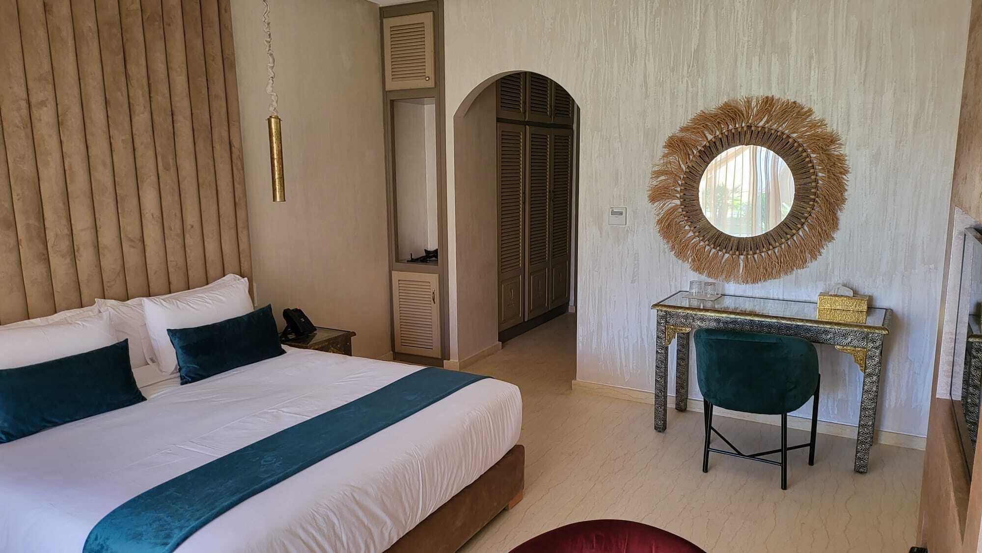 Un dormitorio con una cama grande, un escritorio con silla, un espejo y un armario.