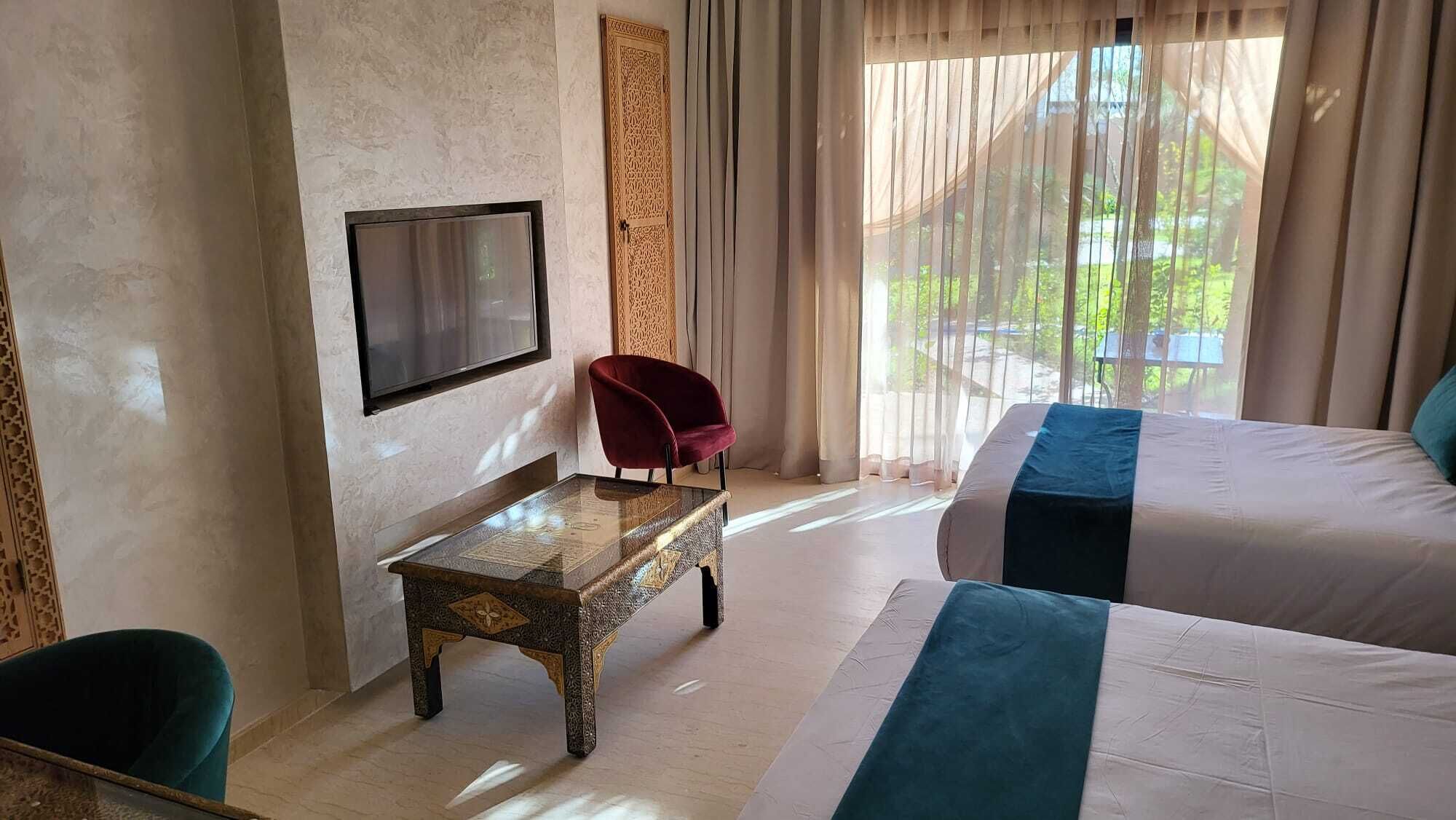 Une chambre d’hôtel avec un lit, une télévision, une petite table et une chaise.