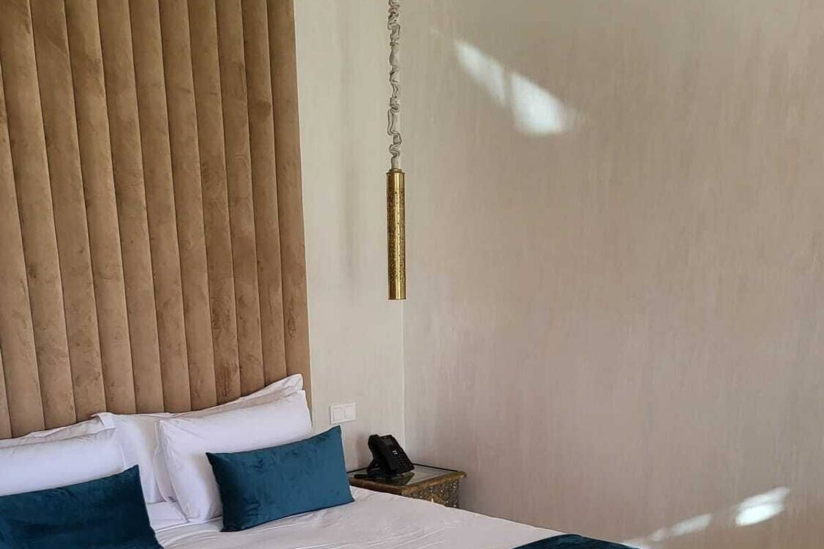 Ein modernes Schlafzimmer mit einem großen Bett, einem Holzkopfteil, einem Nachttisch mit Lampe und einem Deckenventilator.