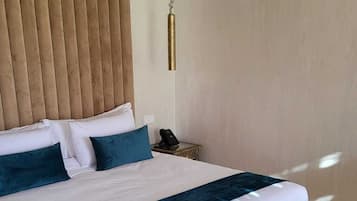 Un dormitorio moderno con una cama grande, un cabecero de madera, una mesita de noche con una lámpara y un ventilador de techo.
