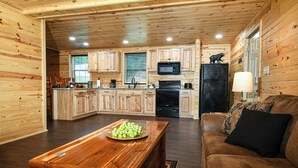 Interior de una cabaña de madera con cocina, comedor y sala de estar.