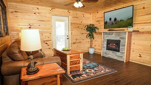 Un acogedor interior de cabaña con detalles de madera, una chimenea, un televisor y un sofá de cuero.