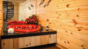 Un interior de madera con una escalera de madera, una bañera roja y un arreglo floral.