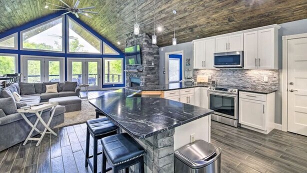 A spacious kitchen with a large island, white cabinets, and a stone backsplash. - Lake Effect on Norris Lake (New Tazewell)