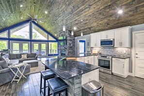A spacious kitchen with a large island, white cabinets, and a stone backsplash. - Lake Effect on Norris Lake (New Tazewell)