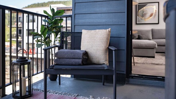 A balcony with a chair, a potted plant, and a lantern. - The Stoke Stopover - Revelstoke Condo with Hot Tub (Revelstoke)
