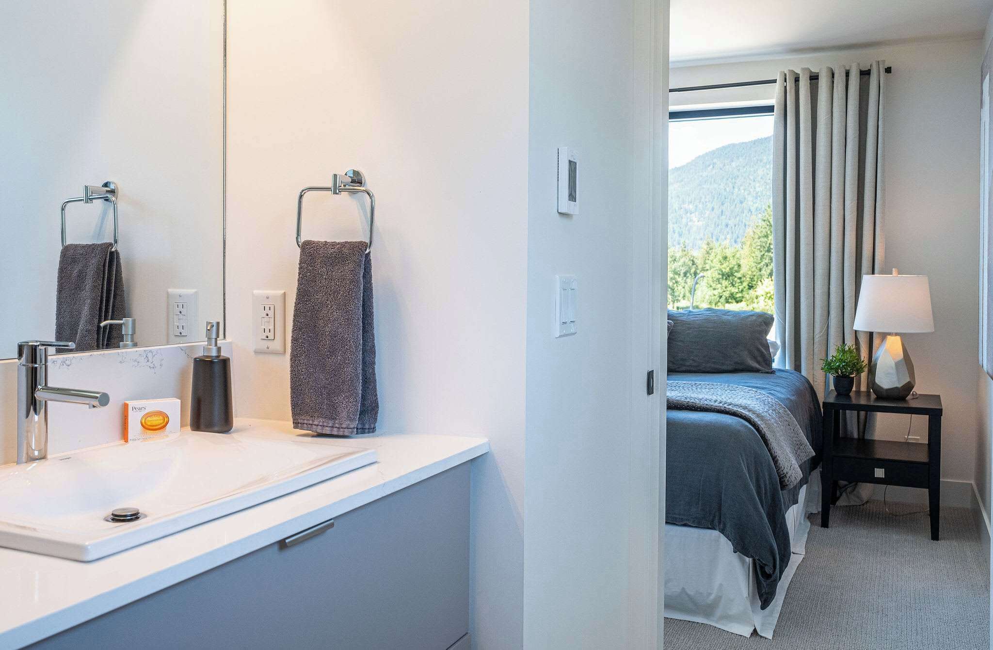 Een moderne badkamer met een witte wasbak, een handdoekhouder en een spiegel.