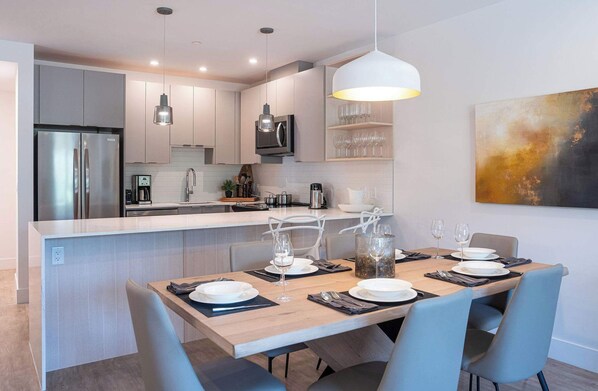 A modern kitchen with a central island, stainless steel appliances, and a dining area set for four.