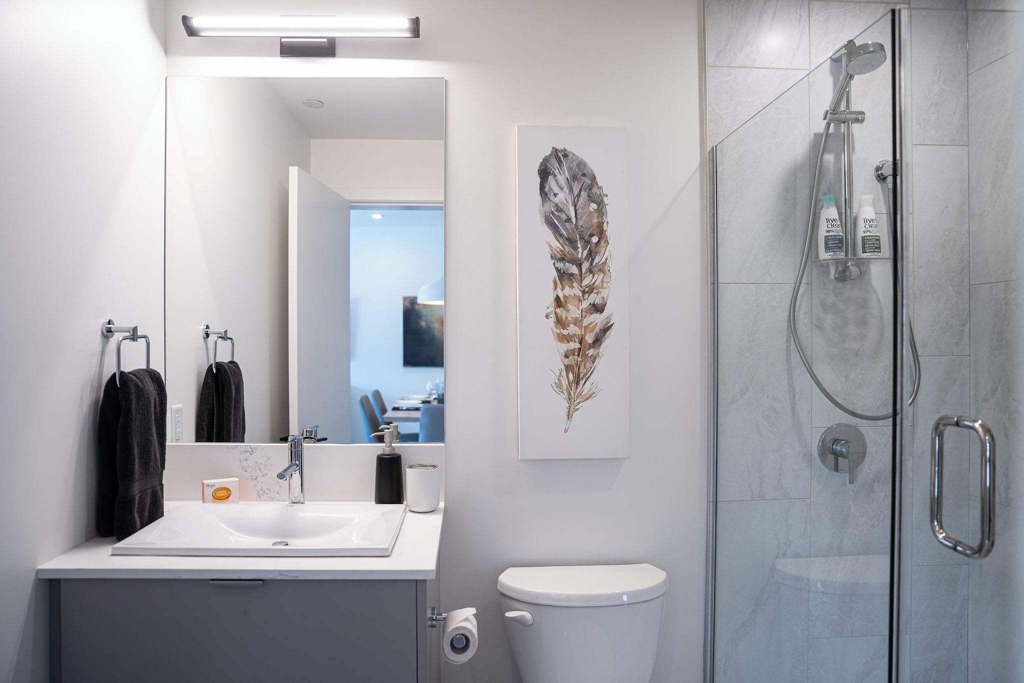 Een moderne badkamer met douche, toilet en wastafel.