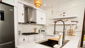 A modern kitchen with a stainless steel refrigerator, a built-in stove, and a white countertop. - Casa Don Toribio: Luxury Home with Private Pool (Aguada)