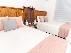 A hotel room with two beds, wooden headboards, a nightstand, a lamp, and a window with blinds. - Casa Don Toribio: Luxury Home with Private Pool (Aguada)