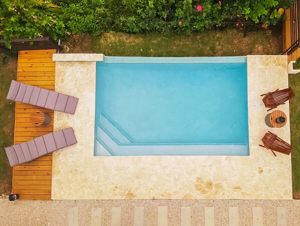 A rectangular swimming pool with a stone border, surrounded by a wooden deck and a stone patio. - Casa Don Toribio: Luxury Home with Private Pool (Aguada)