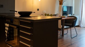 A modern kitchen with a central island, built-in oven, and a dining area with a table and chairs. - M Apartment: Feel good in the charming apartment (Landau in der Pfalz)