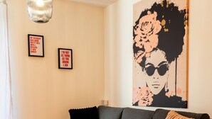 A modern living room with a grey sofa, a round black coffee table, and a large abstract painting on the wall. - M Apartment: Feel good in the charming apartment (Landau in der Pfalz)