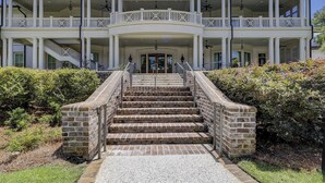 A large, two-story building with a central entrance, a covered porch with columns, and a staircase leading to the entrance.