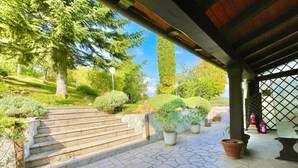 A stone staircase leading to a covered entrance with potted plants and a view of a park. - Mazzetti Country House-Country living and garden (Collina di Savignano)