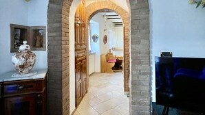 An arched doorway leading to a kitchen area with wooden flooring and a tiled backsplash. - Mazzetti Country House-Country living and garden (Collina di Savignano)