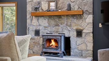 A stone fireplace with a wood-burning stove, a shelf above it, and a framed picture.