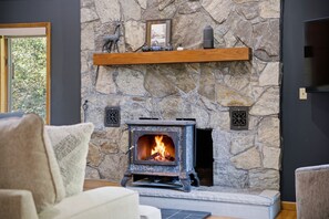 A stone fireplace with a wood-burning stove, a shelf above it, and a framed picture.