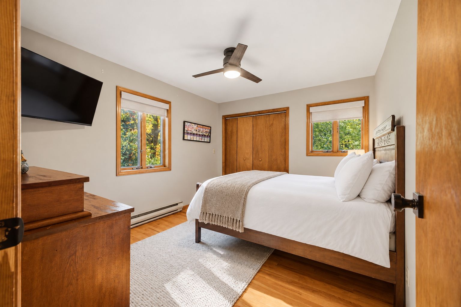 Une chambre à coucher comprenant un lit, un bureau, un téléviseur et un ventilateur de plafond.