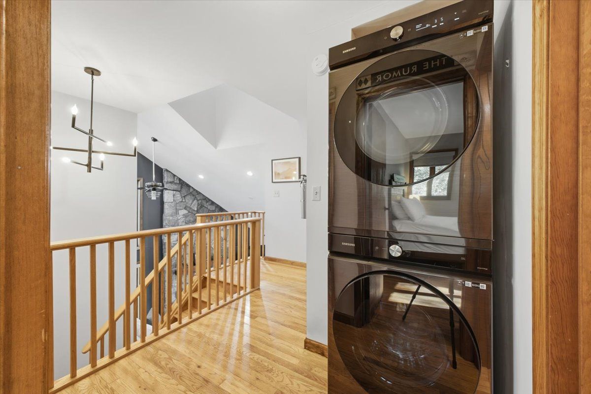 Un intérieur moderne avec un escalier, un appareil combiné lave-linge et sèche-linge intégré et une rambarde en bois.