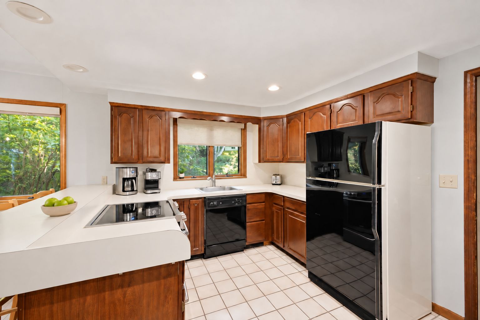 A modern kitchen with wooden cabinets, a stainless steel refrigerator, and a dishwasher.