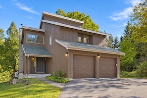 Une maison moderne à deux étages, dotée d’un garage, d’un porche et d’une pelouse bien entretenue.