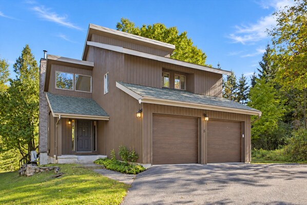 A modern two-story house with a garage, a front porch, and a well-maintained lawn.