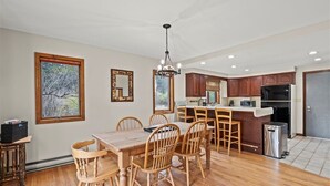 A spacious kitchen with wooden cabinets, a central island, and a dining area with wooden chairs and a table.