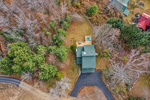 An overhead view shows the house, driveway, deck, and wooded surroundings.