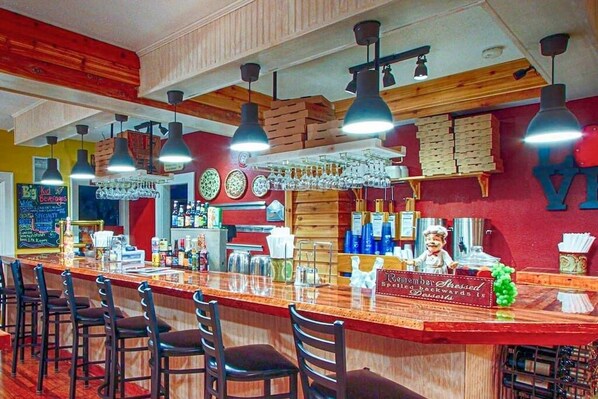 A bar area with a wooden counter, multiple hanging lights, and a sign that reads 'Remember Stressed.'