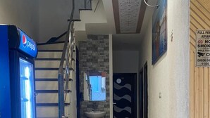 Un pasillo con un refrigerador Pepsi, una escalera, un lavamanos y una silla.