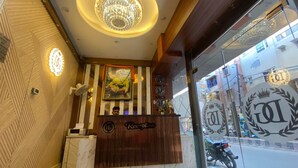 Un área de recepción con un mostrador de madera, una araña de cristal y una puerta de vidrio con adornos decorativos.
