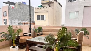 Terraza en la azotea con sofá, mesa de centro y plantas en macetas.