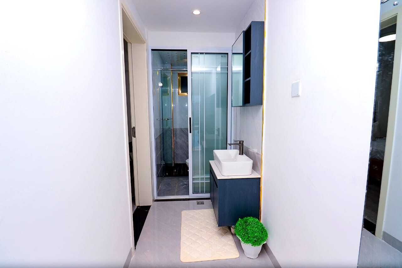Un bagno moderno con cabina doccia in vetro, lavandino bianco e mobile contenitore scuro.