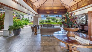 A spacious lobby with a high ceiling, a central seating area, and a view of a landscaped garden. - Summer Reduced! OT-503 Gorgeous Ocean and Pool View Villa! (Kapolei)