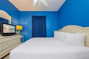 A hotel room with a large bed, a television, a desk, and a ceiling fan. - The Dunes 503 1 Bedroom Condo (Gulf Shores)