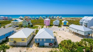 A coastal area with colorful beach houses, a clear blue sky, and a beach in the background. - The Dunes 503 1 Bedroom Condo (Gulf Shores)
