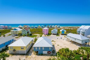 A coastal area with colorful beach houses, a clear blue sky, and a beach in the background. - The Dunes 503 1 Bedroom Condo (Gulf Shores)