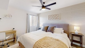 A bedroom with a bed, a desk, a chair, a ceiling fan, and a nightstand with a lamp. - Villa Sunrise 1 Bedroom Condo by RedAwning (Scottsdale)