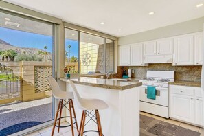 Una cocina moderna con gabinetes blancos, encimera de granito y una isla grande con taburetes de bar.