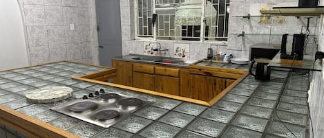 A kitchen with a central island, wooden cabinets, a sink, and a window with decorative tiles.