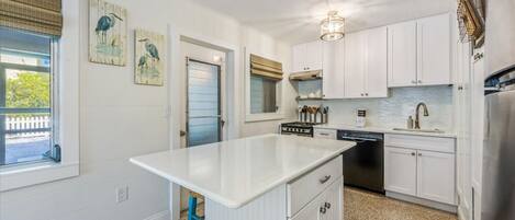 A kitchen with white cabinets, a central island, a dishwasher, and a stainless steel refrigerator.
